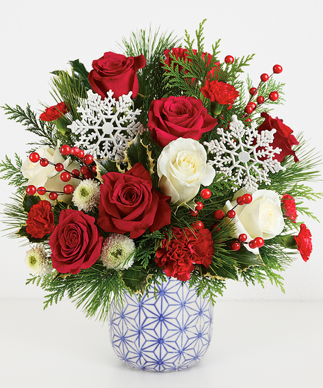 Holiday Petite floral arrangement with red and white roses, carnations, and a snowflake in a blue patterned vase