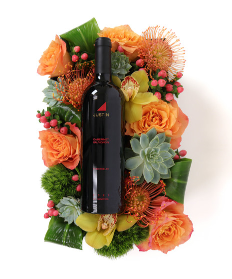 Desert Radiance BloomBox featuring orange and yellow roses, orchids, pincushion proteas, succulents, and greenery in a wooden crate